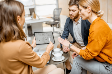 Frisco move-up buyers with their real estate advisor discussing a family-friendly floor plan at a sunlit kitchen island