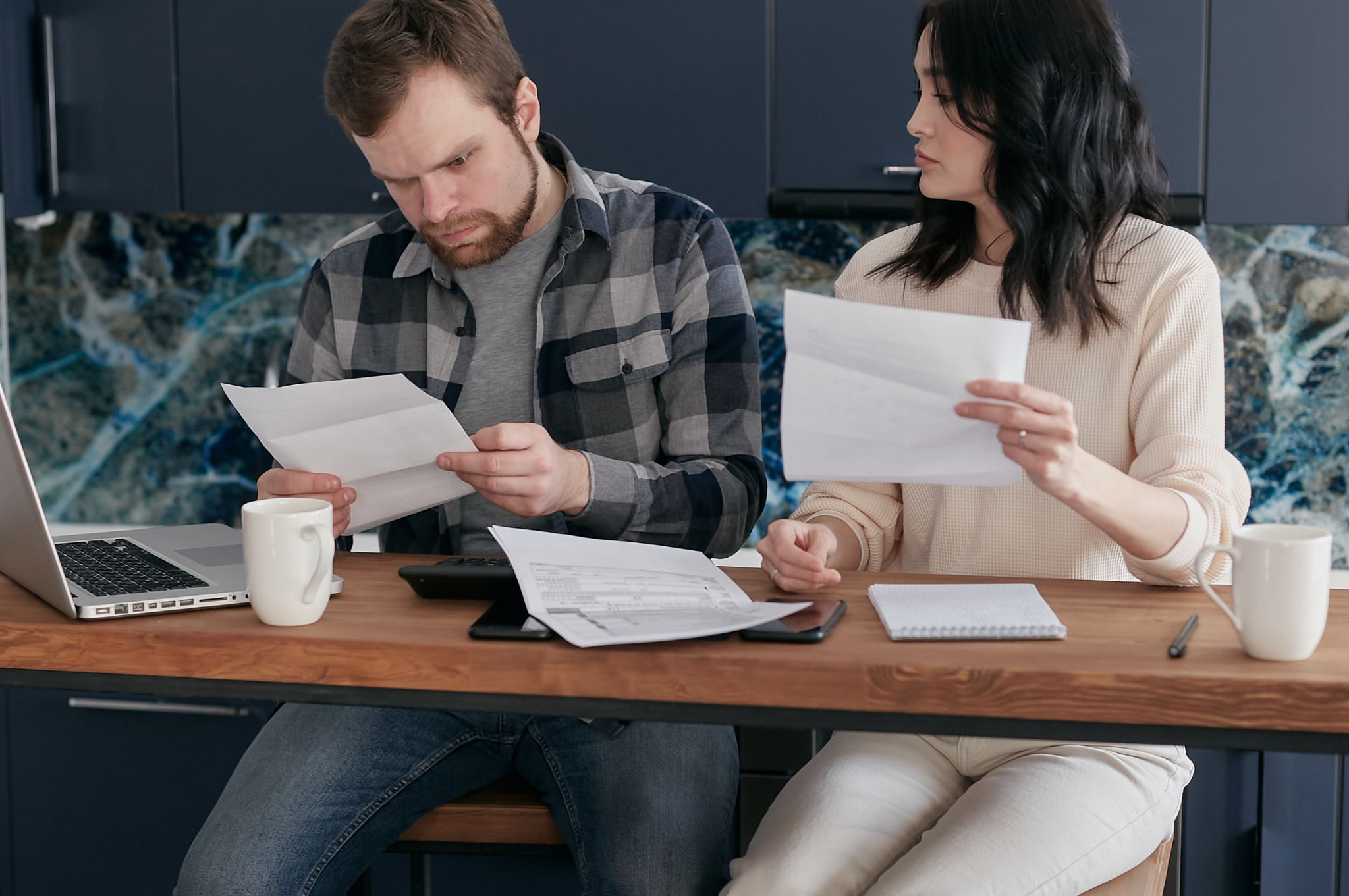 Older Plano homeowner reviewing property tax statements and a home-sale planning worksheet with an advisor at a bright kitchen table